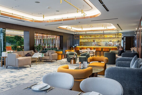 Un moderno vestíbulo de hotel con zona de bar, asientos y vistas al exterior.