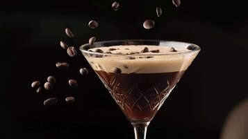 A martini glass with a layered drink on a dark marble table.