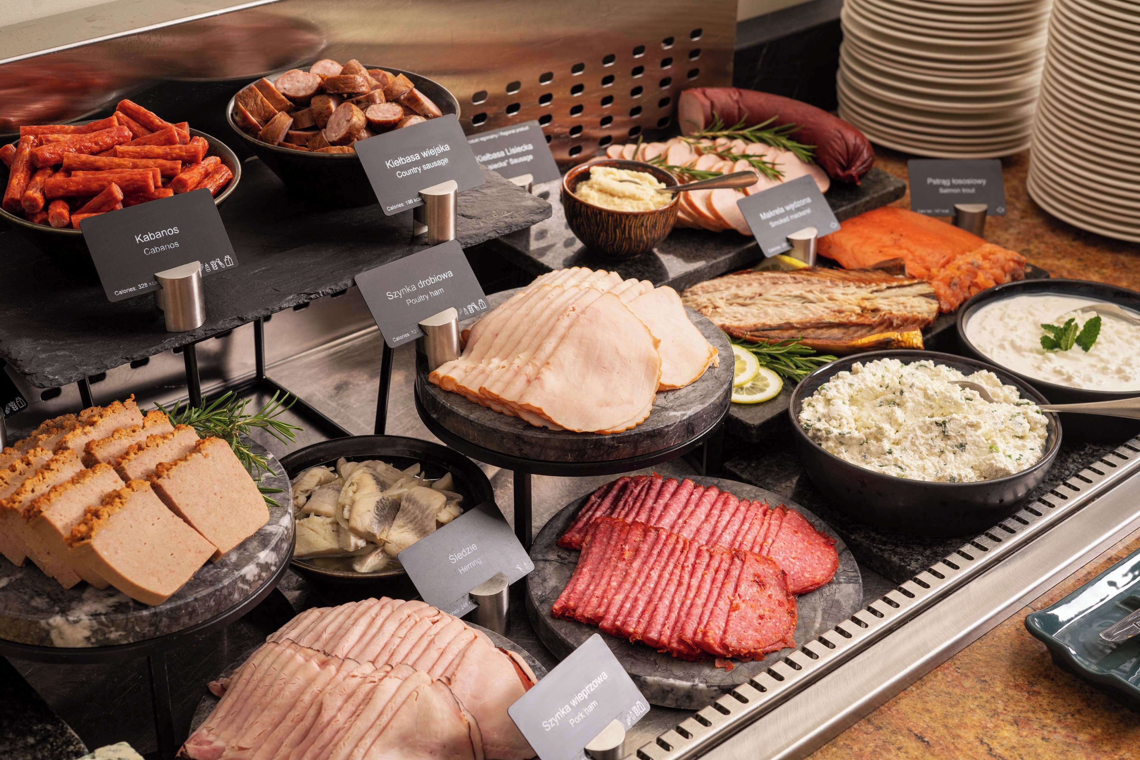 A buffet with various meats and cheeses, including kielbasa, smoked salmon, and ham.