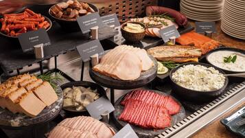 A buffet with various meats and cheeses, including kielbasa, smoked salmon, and ham.