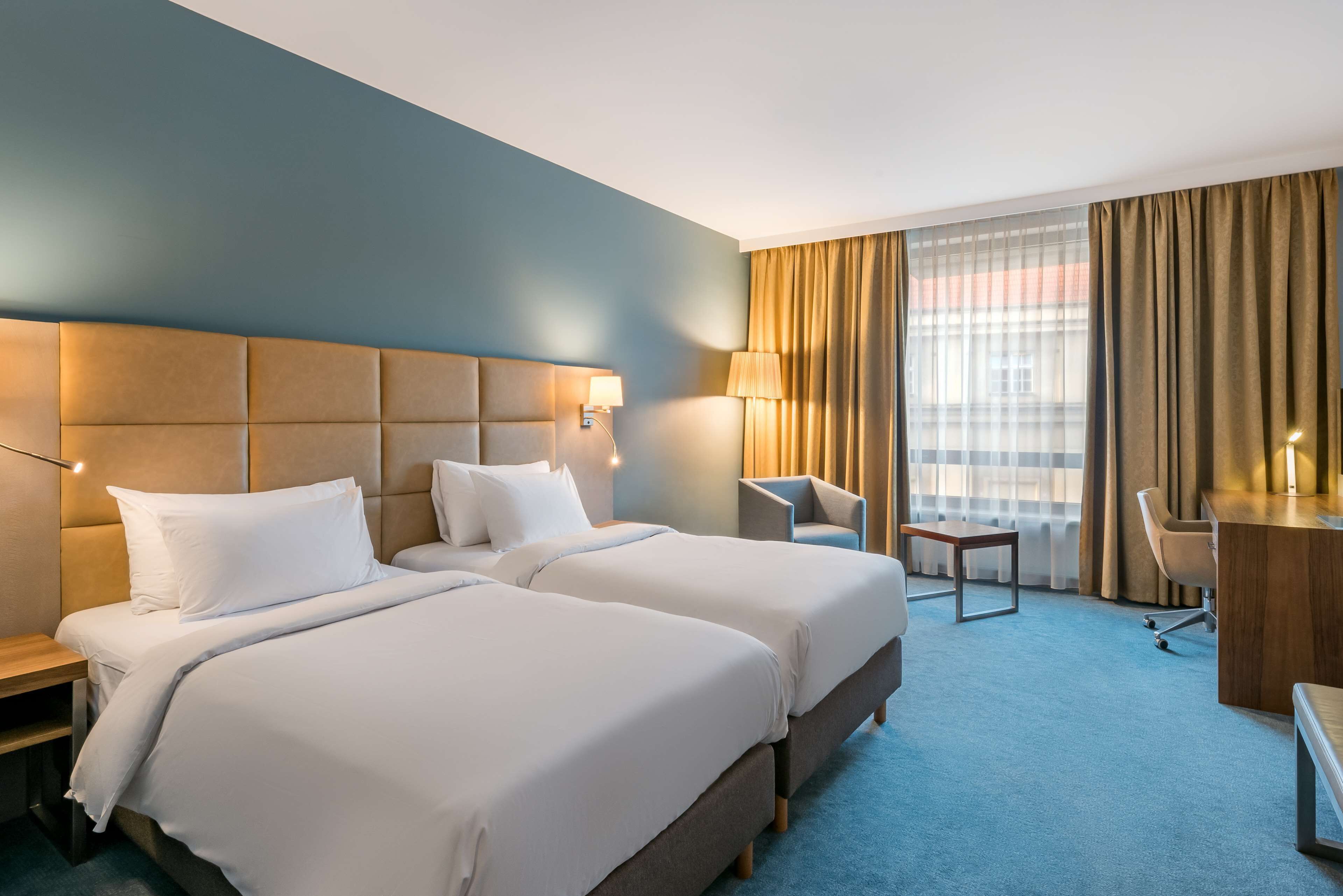 Een hotelkamer met twee bedden, een bureau, een stoel en een kleine tafel.