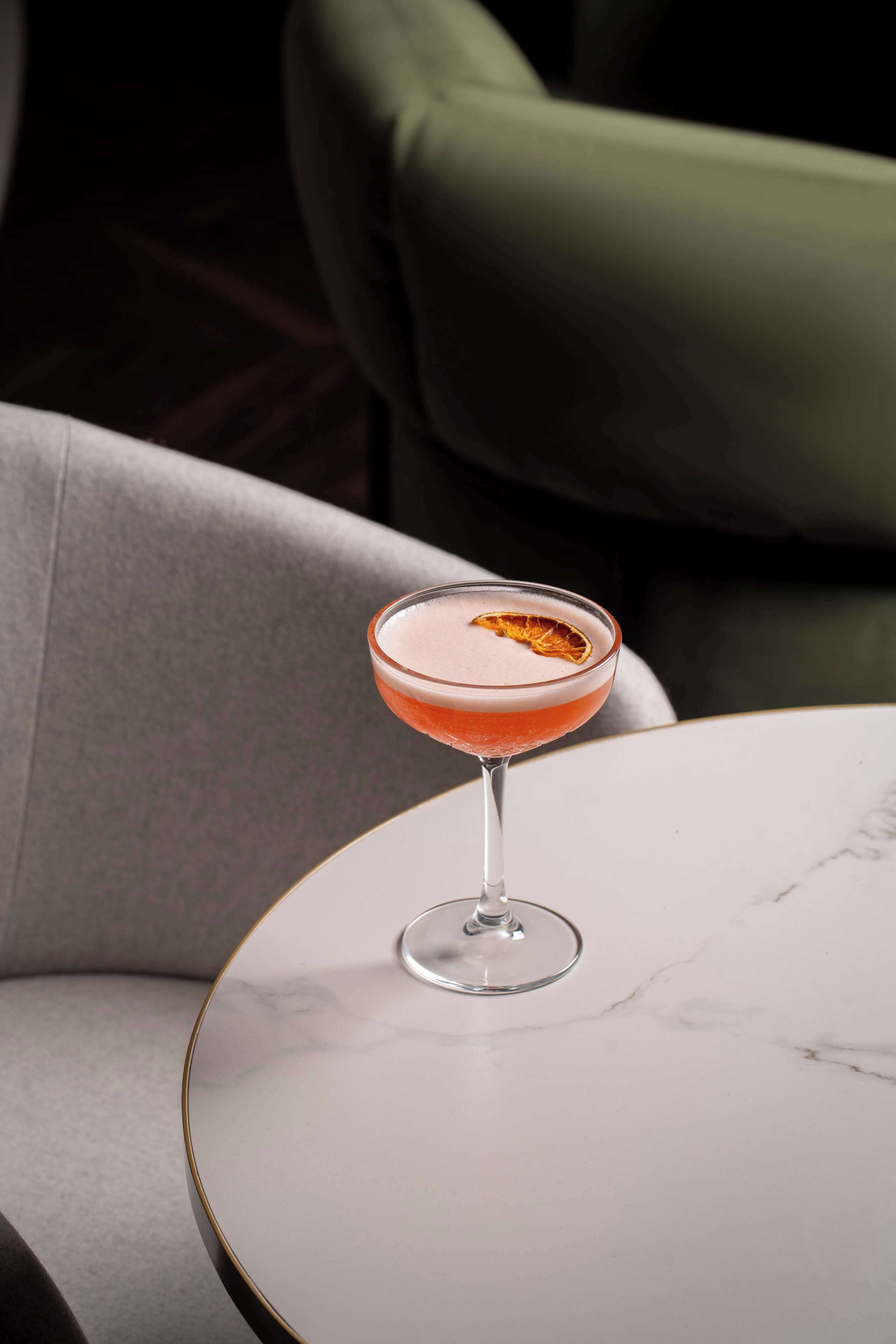 A cocktail in a martini glass on a marble table.