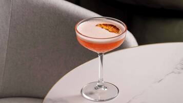 A cocktail in a martini glass on a marble table.