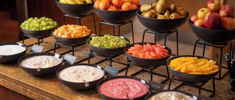 A buffet with various fruits and dips.