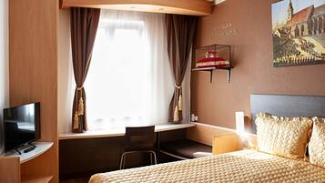 Ein Hotelzimmer mit Bett, Schreibtisch, Stuhl, Fernseher und einem Gemälde von Bratislava.