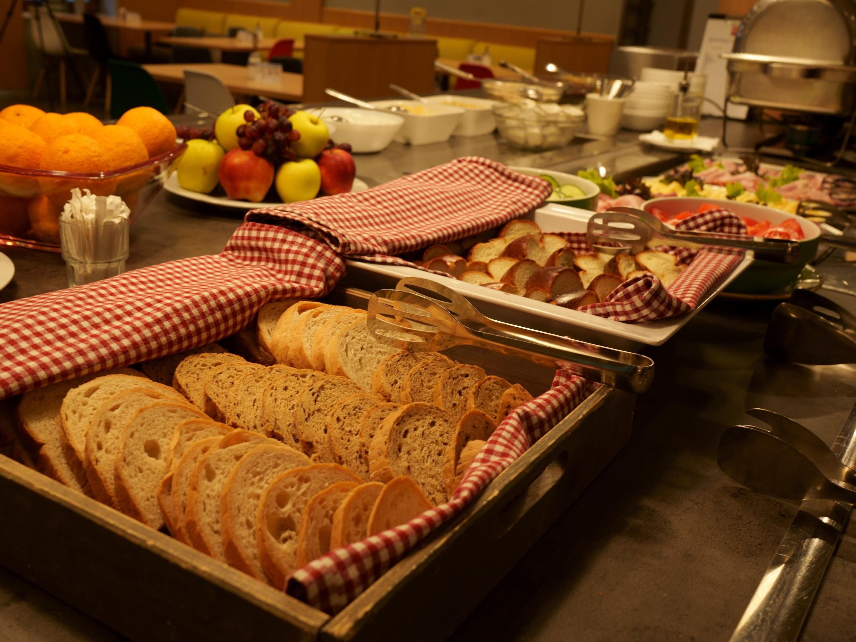 A buffet with various food items including bread, fruits, and salads.