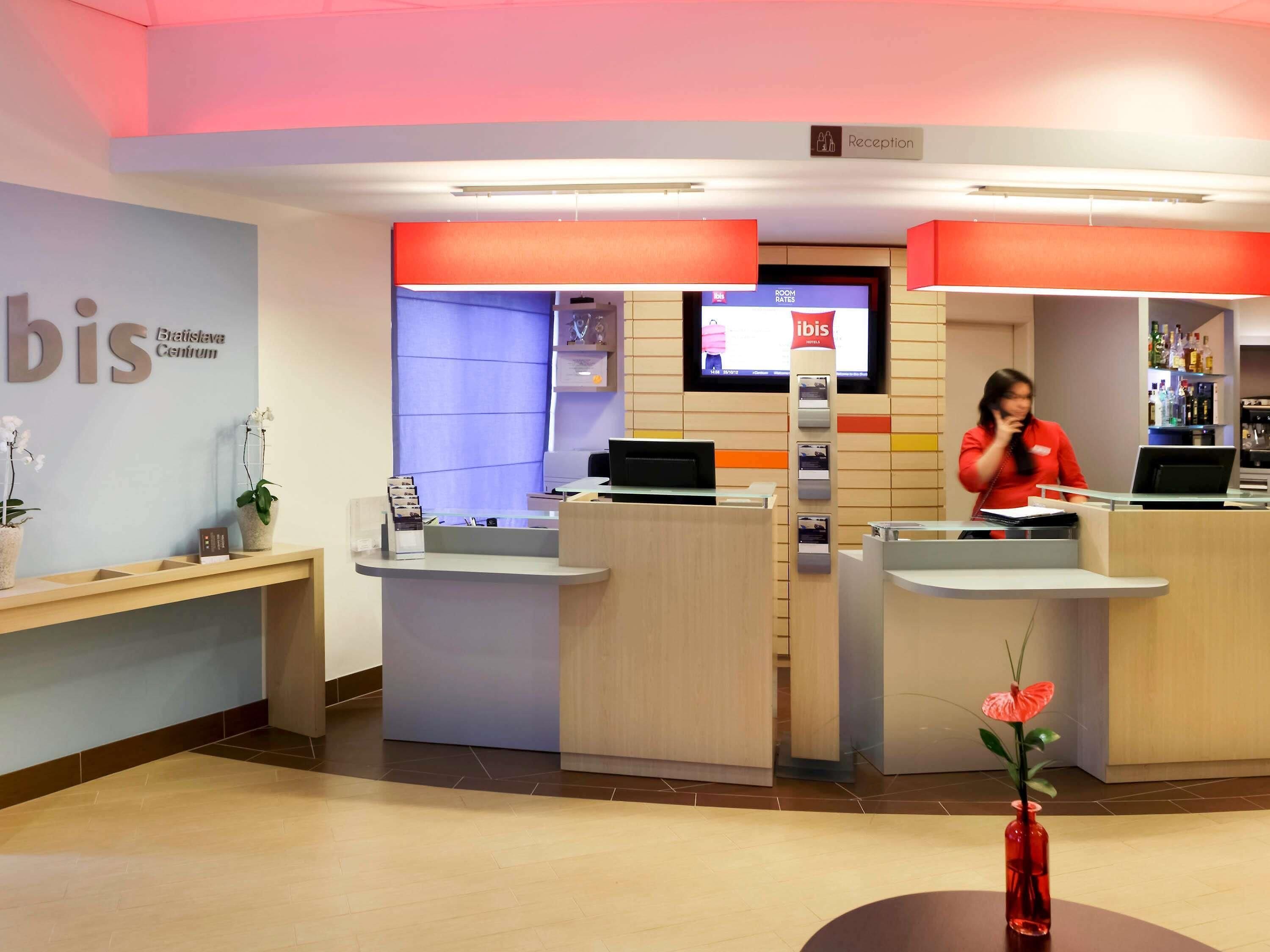A reception area with a digital display, a reception desk, and a sign for 'Bratislava Centrum'.