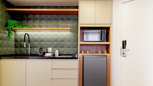 Una cocina compacta con microondas integrado, un lavamanos y un refrigerador pequeño.
