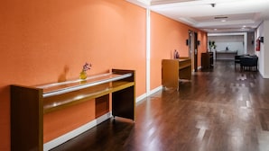 Un vestíbulo de hotel con un mostrador de recepción de madera, un jarrón con flores y una zona de recepción con un escritorio y sillas.