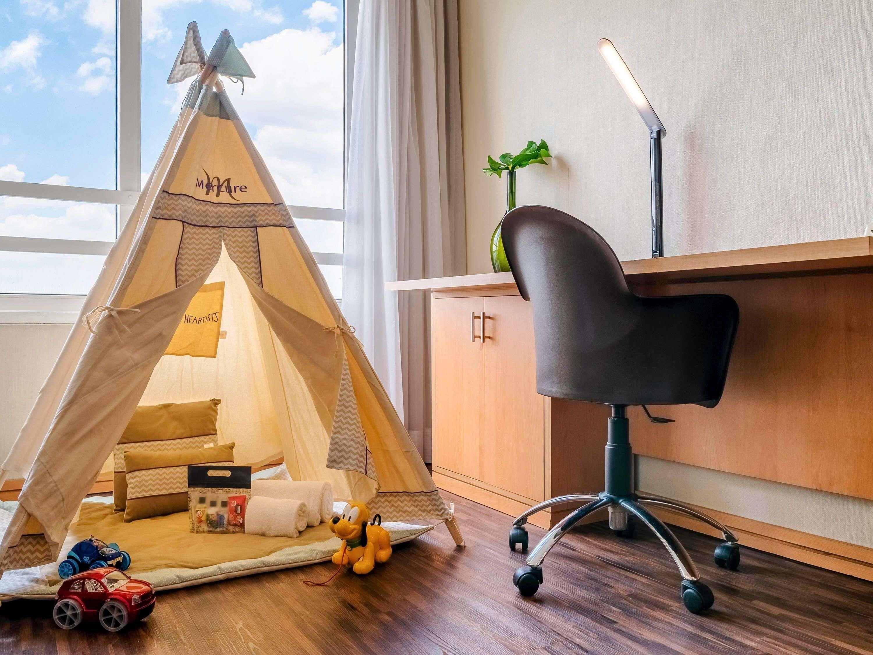 Una habitación con una tienda de campaña, un escritorio, una silla y juguetes.