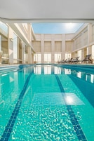 Una piscina al aire libre, sombrillas, sillones reclinables de piscina