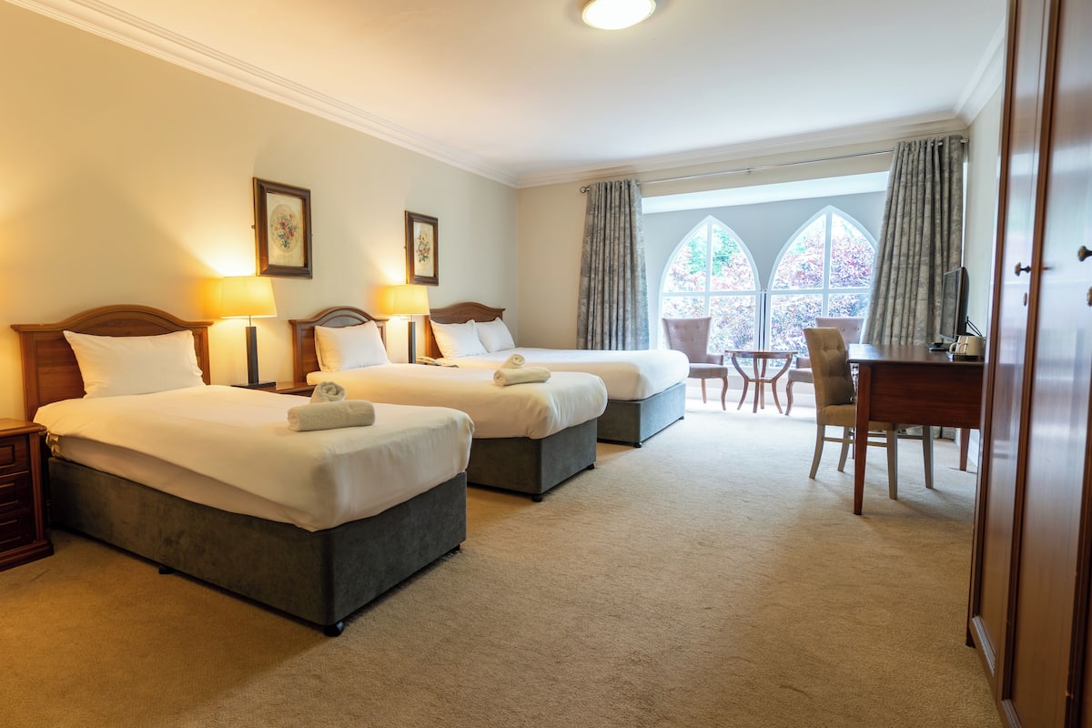 A hotel room with two beds, a desk, and a chair.