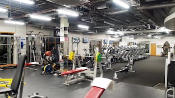 Un gimnasio con diversos equipos de ejercicio, cintas de correr y máquinas de pesas.
