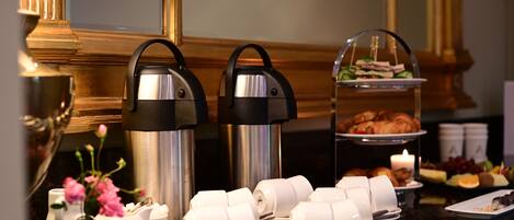 A buffet setup with coffee urns, tea cups, and a sandwich display.