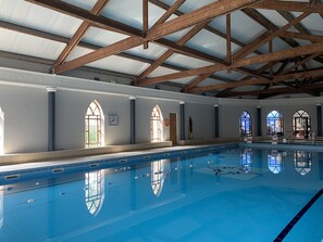 An indoor swimming pool with a high ceiling, wooden beams, and arched windows. - Abbey Court (Nenagh)