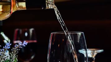 A bottle of white wine being poured into a glass on a wooden table.