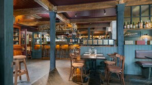 A bar area with wooden stools, a bar counter, and shelves with bottles. - Abbey Court (Nenagh)