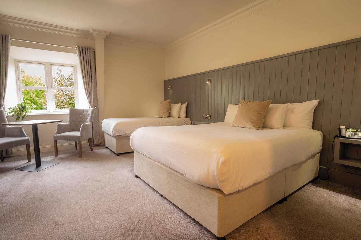 A hotel room with two beds, a desk, and a chair.