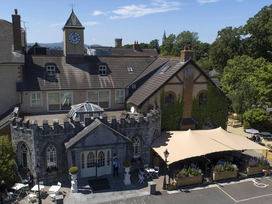 A historic building with a clock tower, a courtyard with outdoor seating, and a castle-like structure.