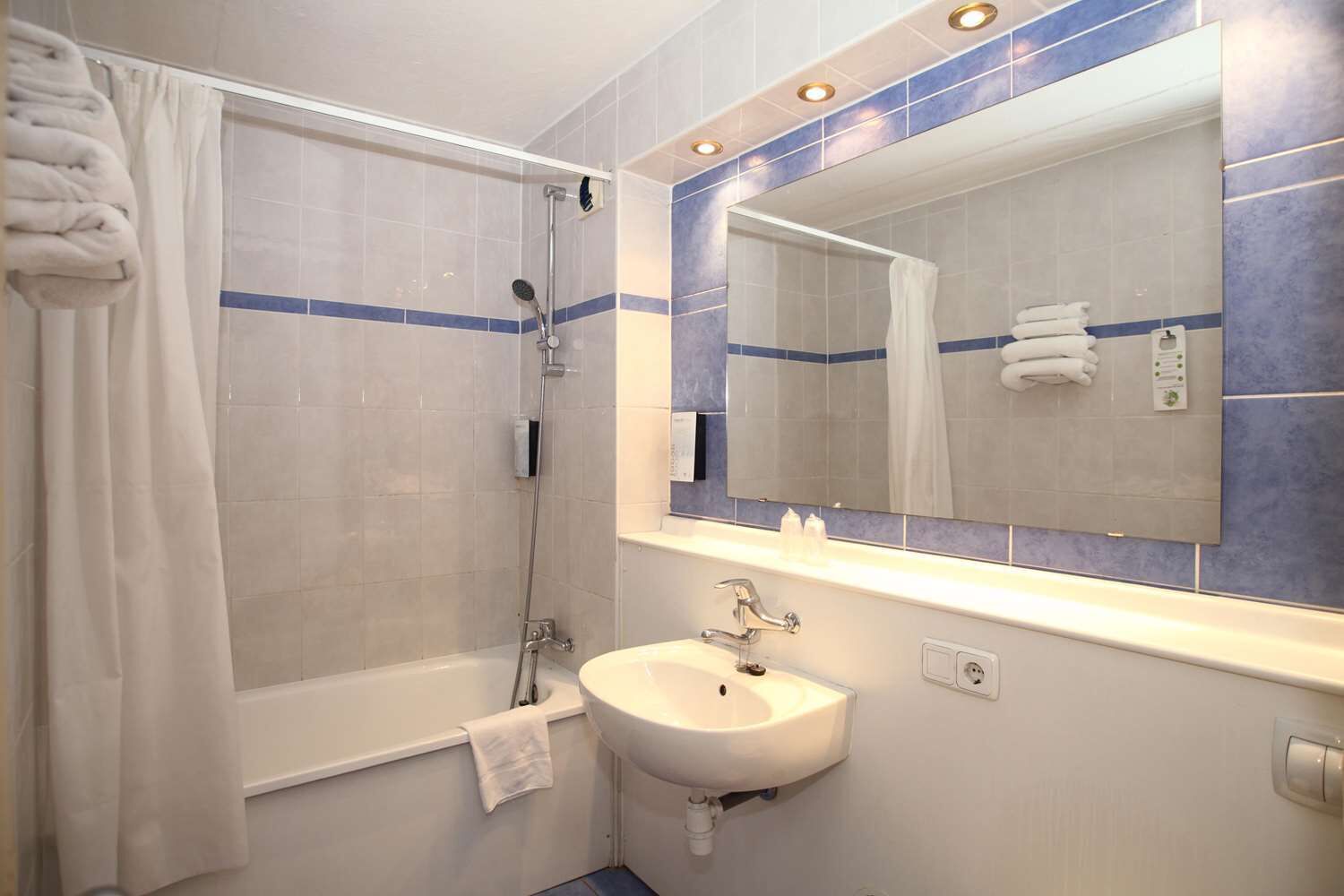 A bathroom with a bathtub, a sink, and a mirror.