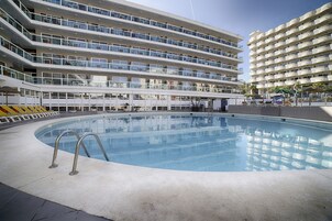 Um hotel com vários andares, piscina, varandas e área de recreação infantil.