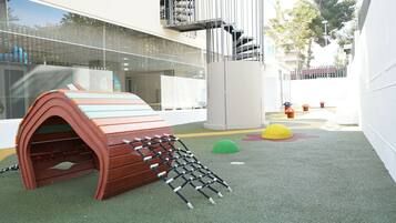 Ein Kinderspielbereich mit Klettergerüst, weichen Spielmatten und einer kleinen Rutsche.