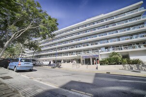 Ένα πολυώροφο ξενοδοχείο με μοντέρνο σχεδιασμό, που διαθέτει μπαλκόνια σε κάθε όροφο και μια κεντρική είσοδο.