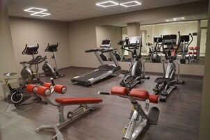 Un gimnasio con diferentes equipos de ejercicio, incluyendo cintas de correr, bicicletas estáticas y máquinas de pesas.