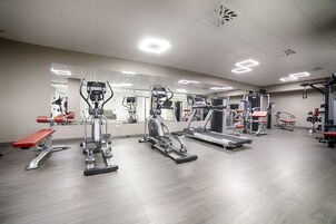 Un gimnasio con diversos equipos de ejercicio, incluyendo cintas de correr, elípticas y máquinas de pesas.