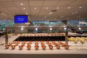 A buffet area with various food items and a digital screen displaying the hotel's name.