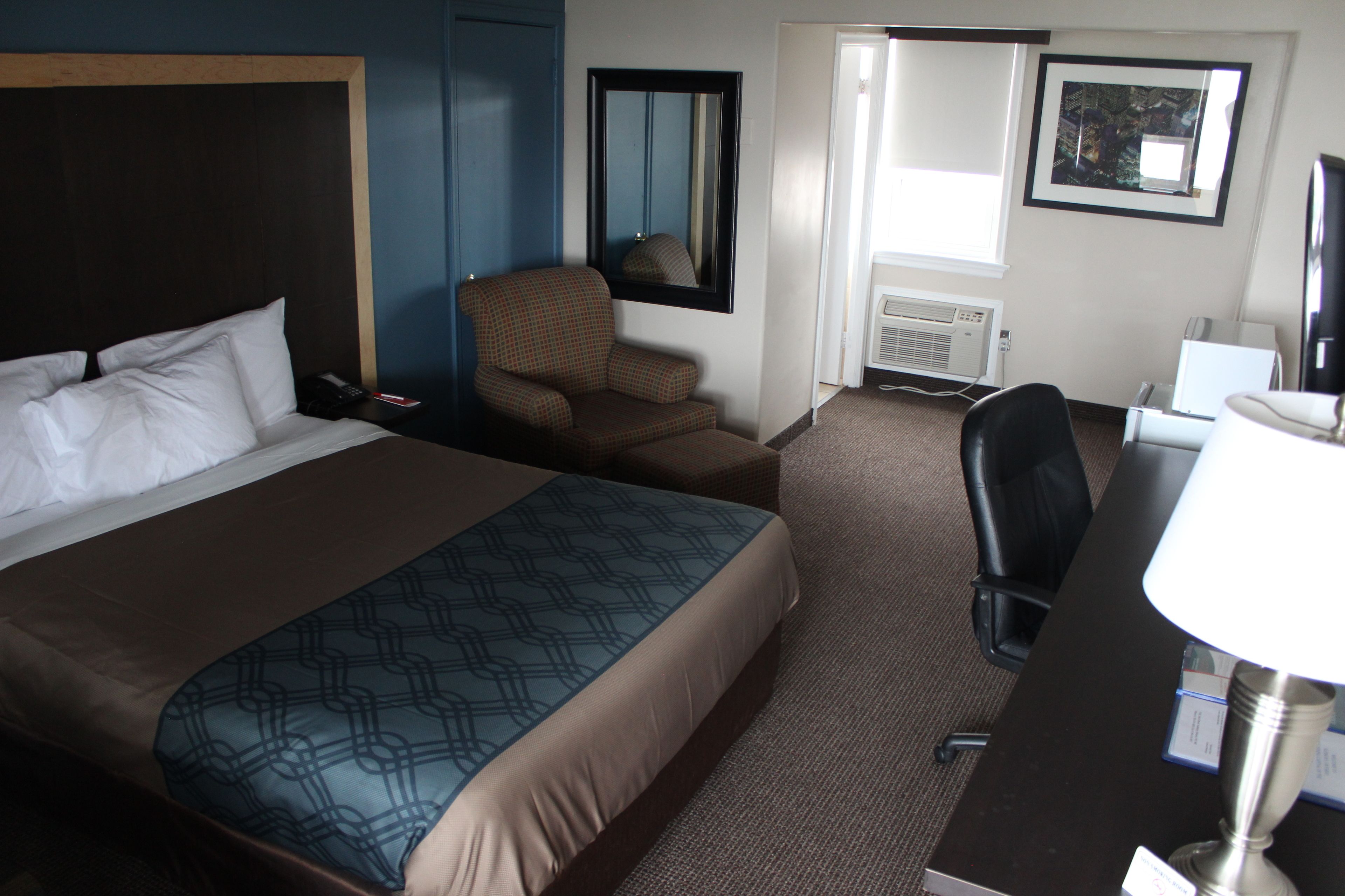 Une chambre d’hôtel avec un grand lit, une chaise, un bureau et un miroir.