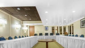 A conference room with a long table, blue chairs, and a wooden table in the center. - Econo Lodge (Sudbury)