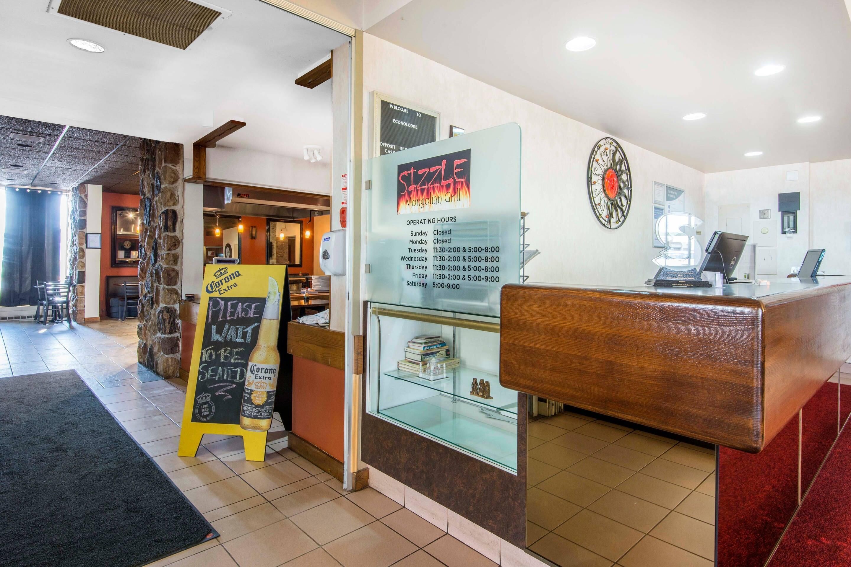 A restaurant interior with a glass display case, a chalkboard sign, and a wooden counter.