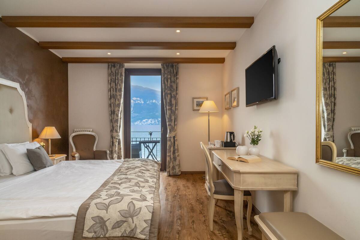 Habitación de hotel con una cama grande, un escritorio, una silla, un televisor y vistas a las montañas.