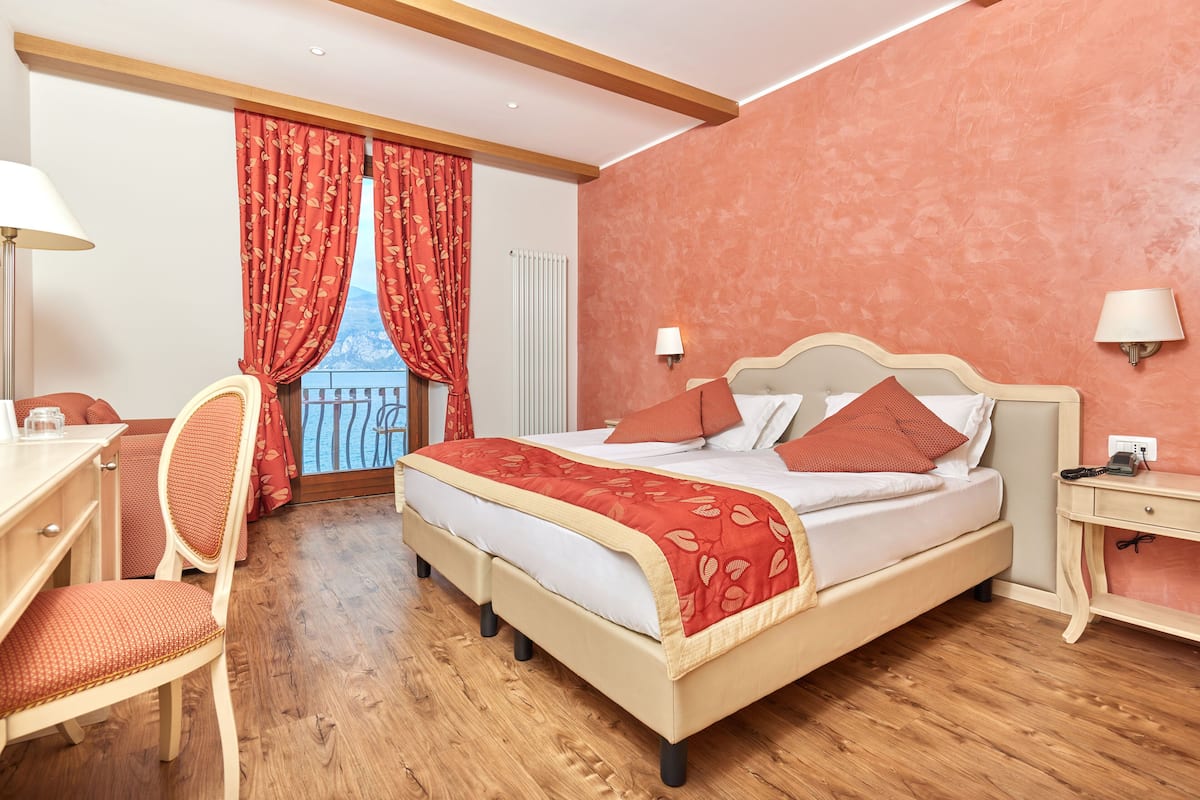 Un dormitorio con cama, escritorio, silla y ventana con cortinas.