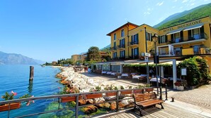 Un hotel frente al mar con terraza al aire libre y una montaña en el fondo.