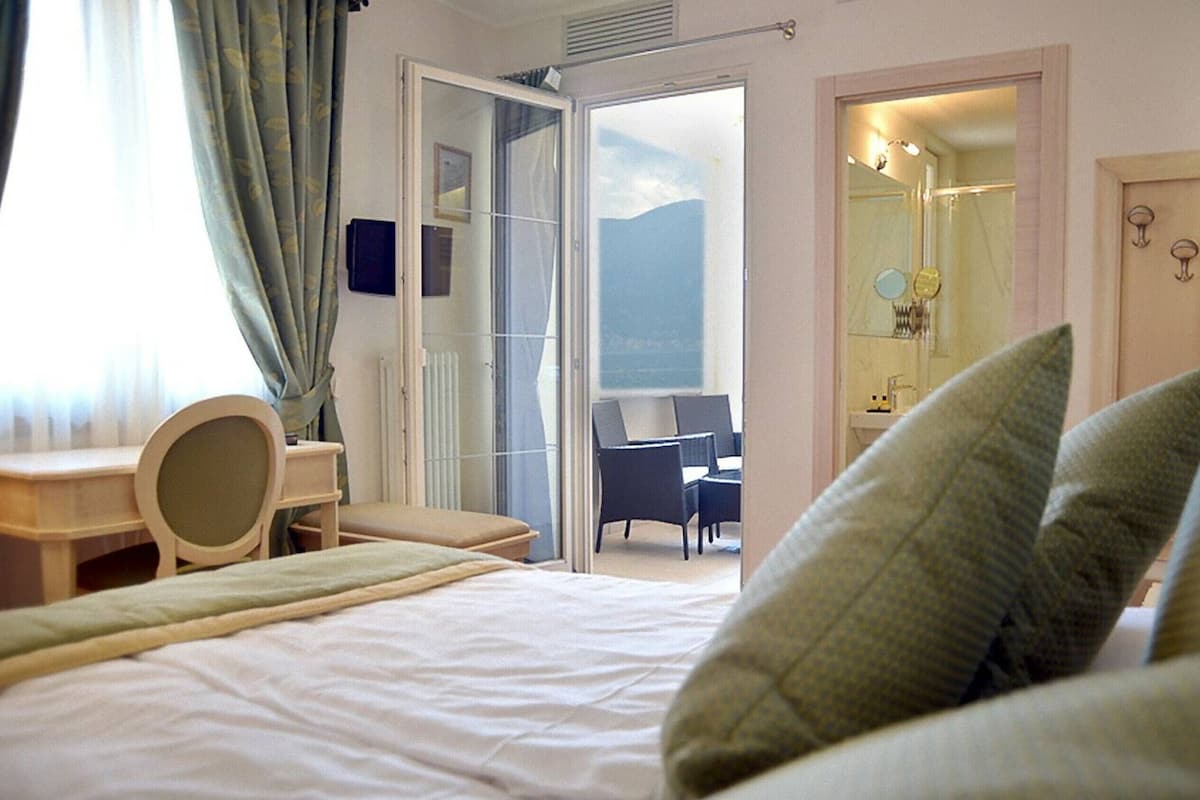 Habitación de hotel con cama, escritorio y baño visible a través de una puerta abierta.