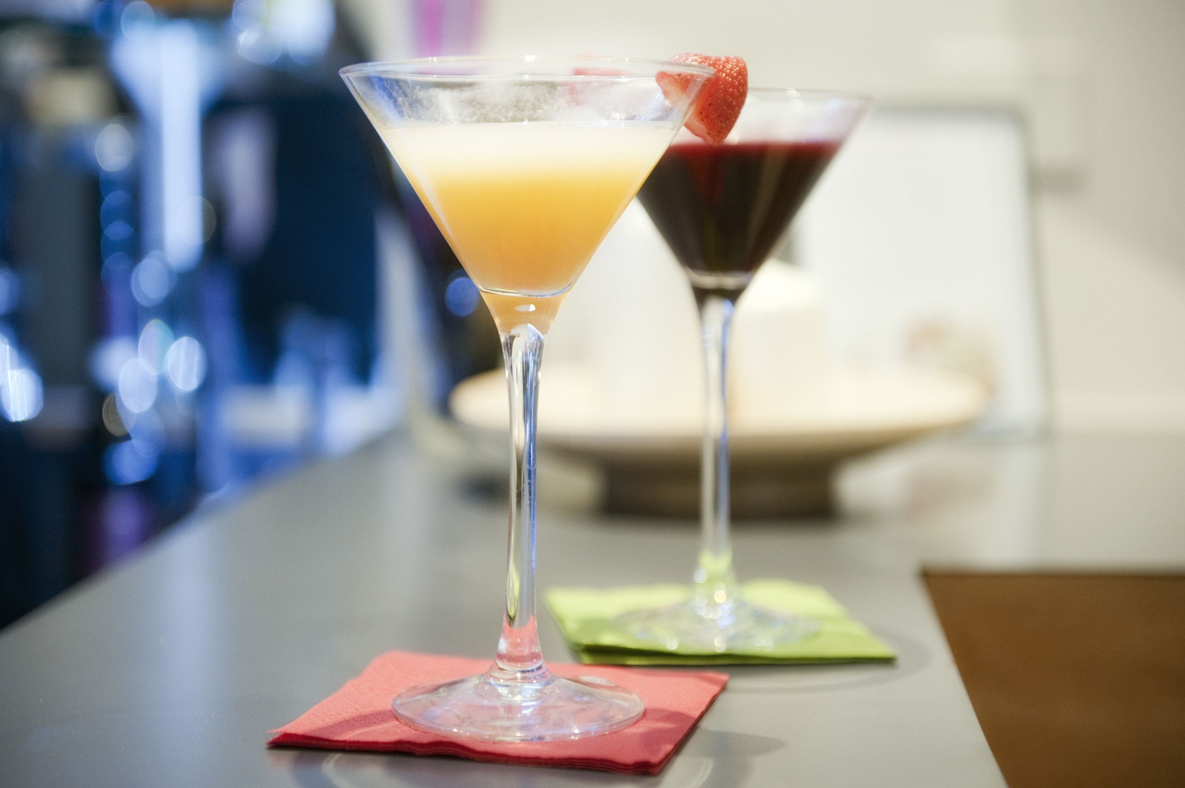 Zwei Martini-Gläser auf einer Bar, unscharfer Hintergrund.