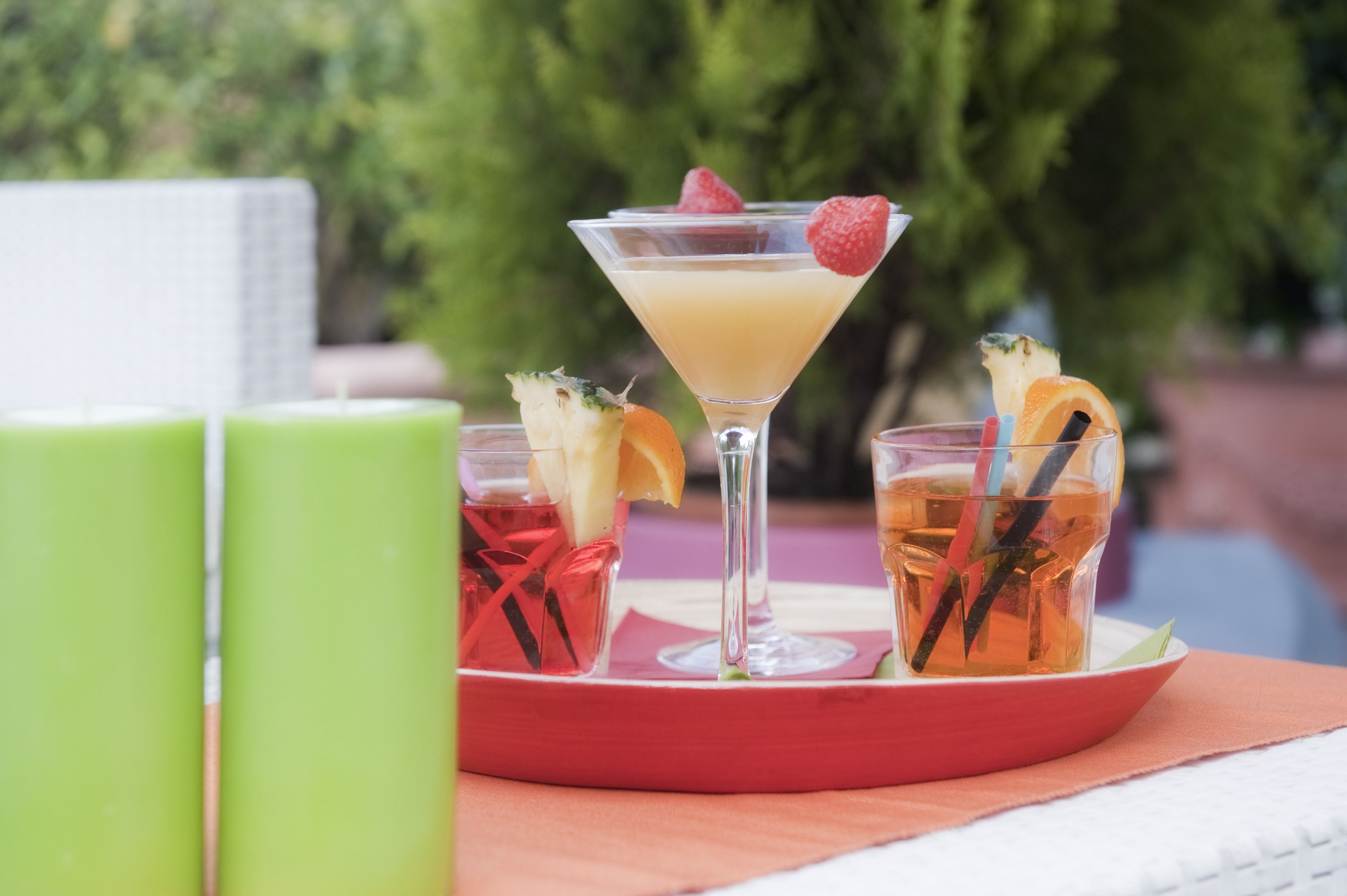 Un vassoio con un bicchiere da martini, due bicchieri con guarnizioni di frutta e una tazza verde.