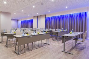 Un salón de conferencias con mesas, sillas y botellas de agua.