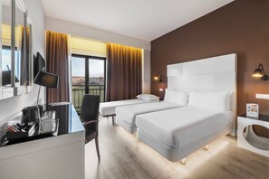 A hotel room with two beds, a desk with a computer, a chair, a TV, and a window with curtains. - Elba Madrid Alcalá (Madrid)