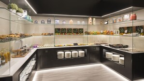 Un ricco buffet per la colazione in stile moderno, con vetrine in vetro, cibi disposti con cura e una vasta scelta di bevande.
