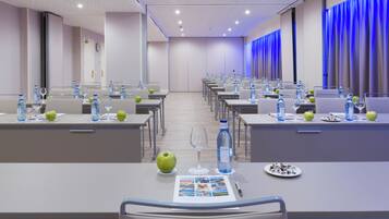 A conference room with tables set for a meeting, equipped with water bottles, glasses, and apples.