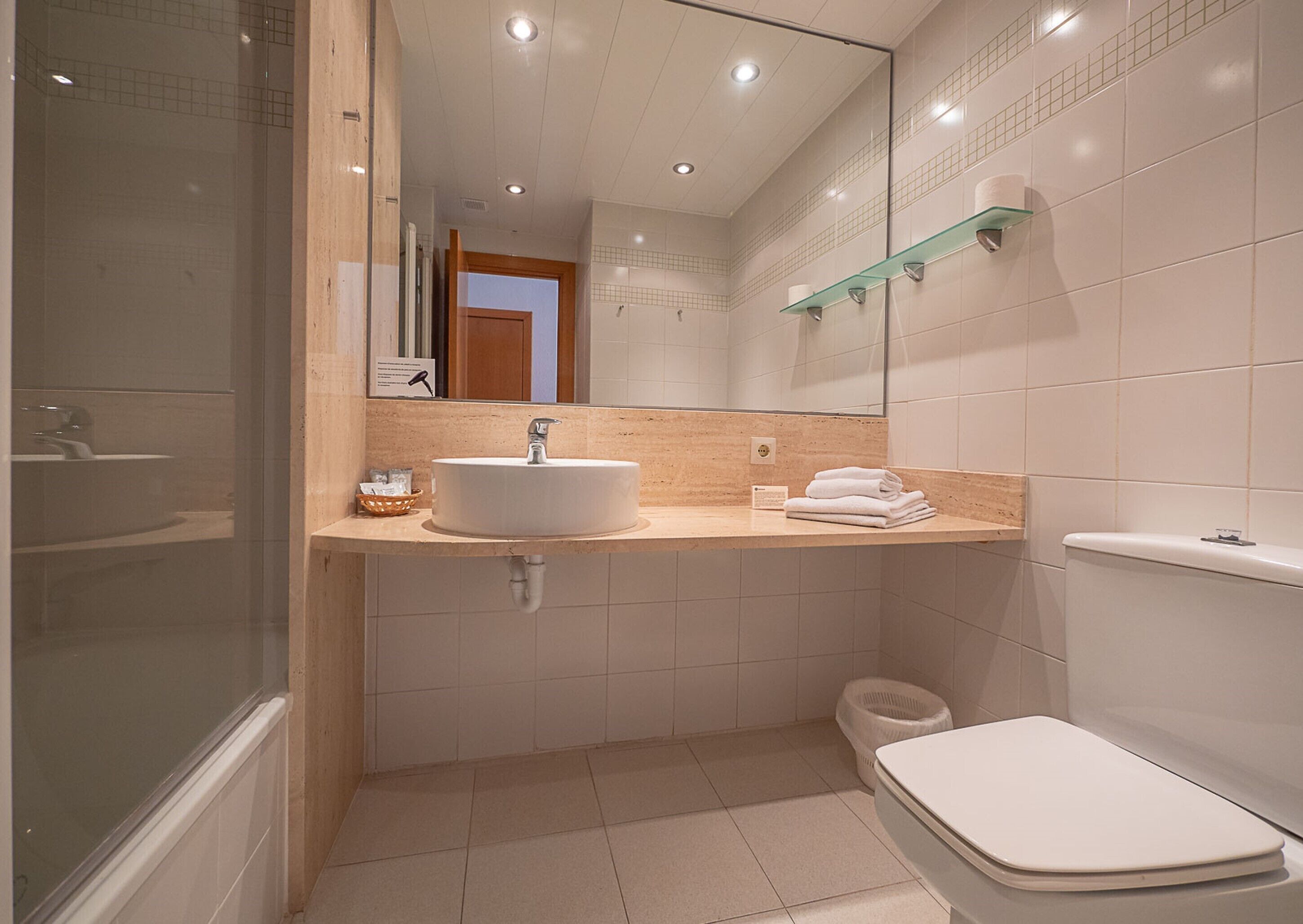 A modern bathroom with a sink, mirror, and toilet.