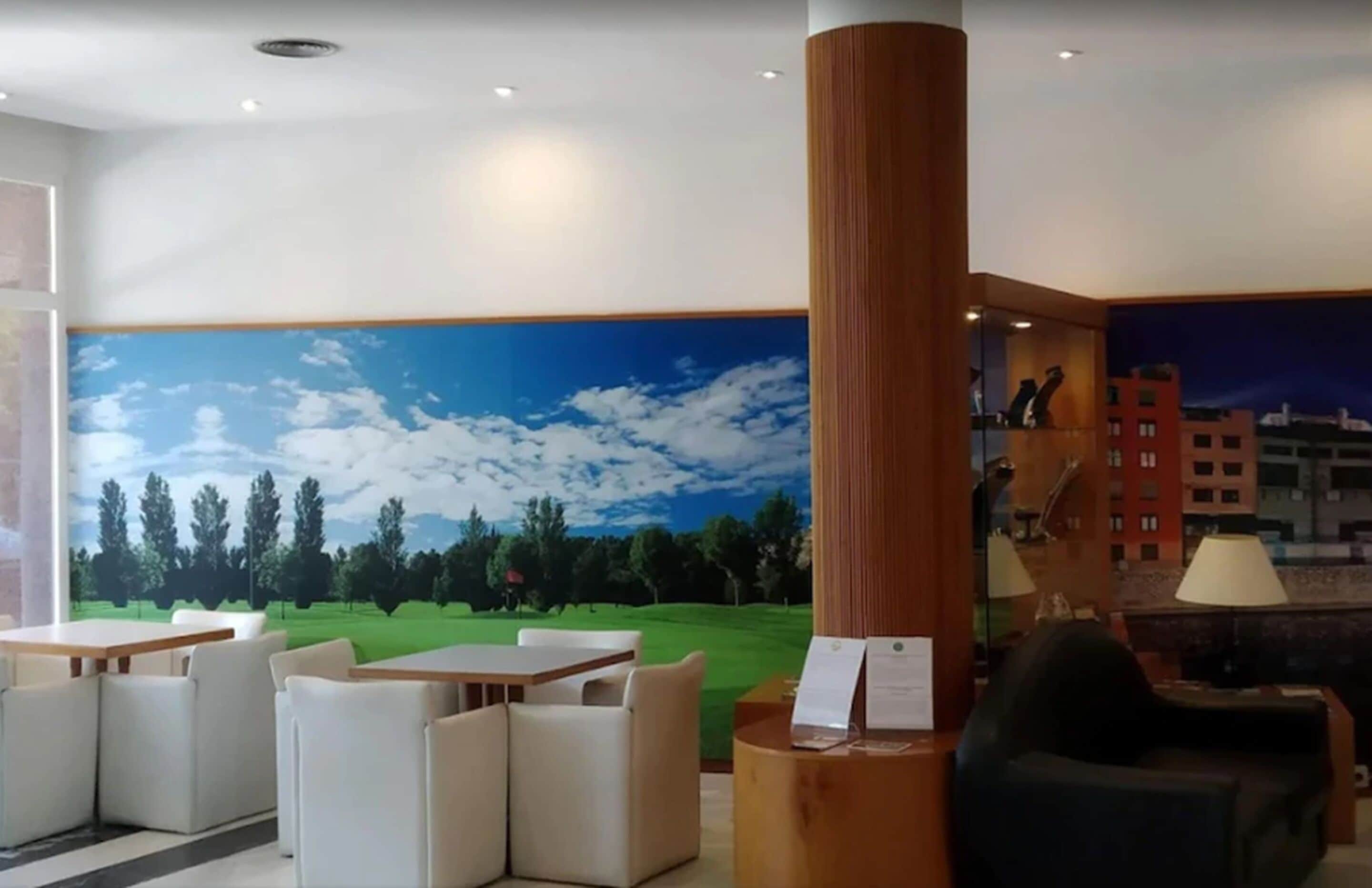 Un vestíbulo con un mural de un campo de golf, un mostrador de recepción de madera y zonas de estar.