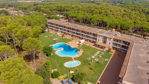 Vue aérienne d’un hôtel doté d’une piscine, de nombreux balcons et d’un paysage environnant.