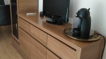 Un mueble de madera con un televisor de pantalla plana, una cafetera y una balanza encima.
