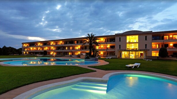 Un hôtel doté de nombreux balcons, d’une piscine et d’une pelouse bien entretenue.