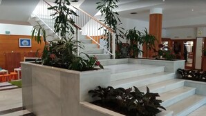 Un hall d’hôtel avec un escalier, des plantes d’intérieur et un mur en bois.
