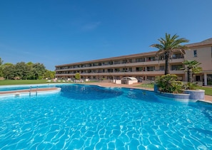Relax by the hotel's large pool surrounded by lush greenery and palm trees.